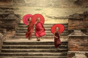 tre barn med røde solparaplyer som går ned en trapp i myanmar