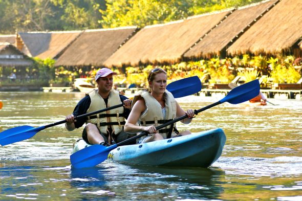 to personer padler på elven med jungle raft hotell i bakgrunnen